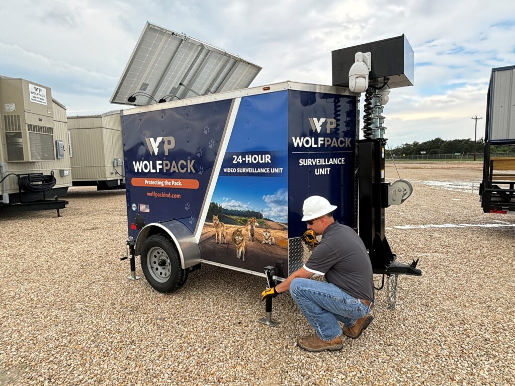 Technician stabilizing and leveling a surveillance trailer.