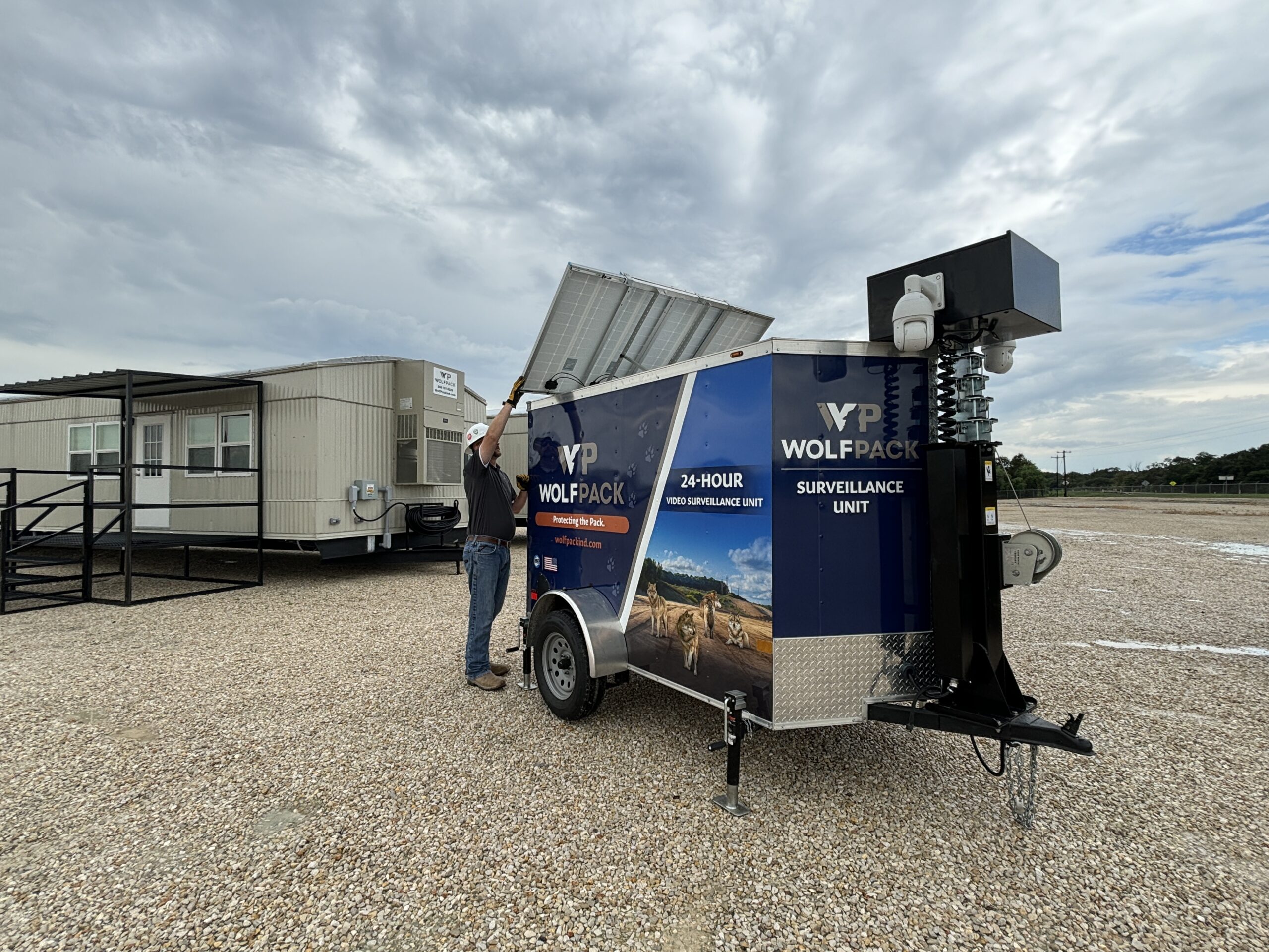 Technician adjusting solar panel on a mobile surveillance trailer.