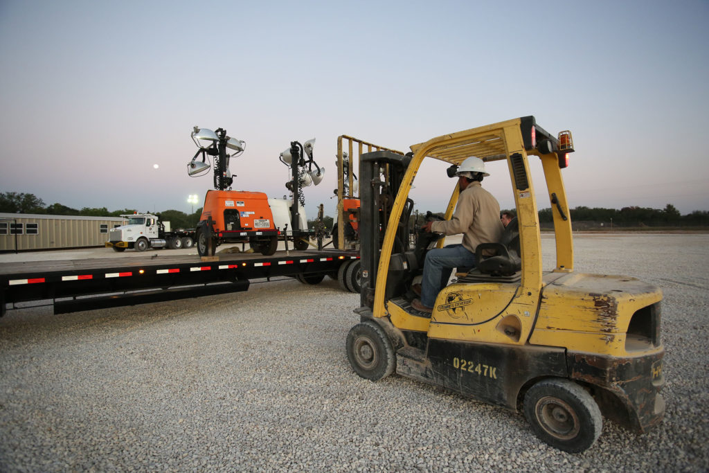 Forklift removing WolfPack light towers from trailer.